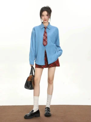 Women's blue retro tie oversized long sleeve streetwear shirt styled with a red plaid mini skirt and loafers