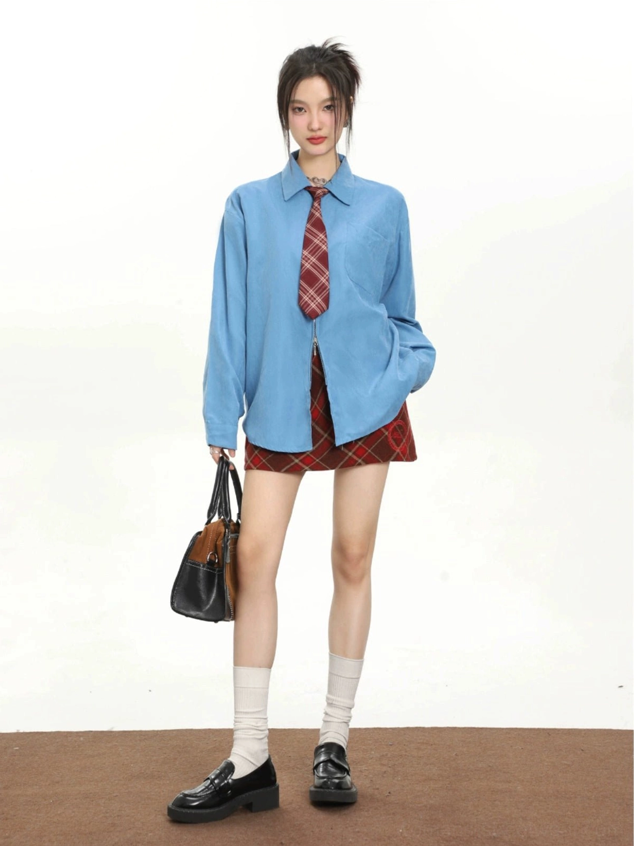 Women's blue retro tie oversized long sleeve streetwear shirt styled with a red plaid mini skirt and loafers