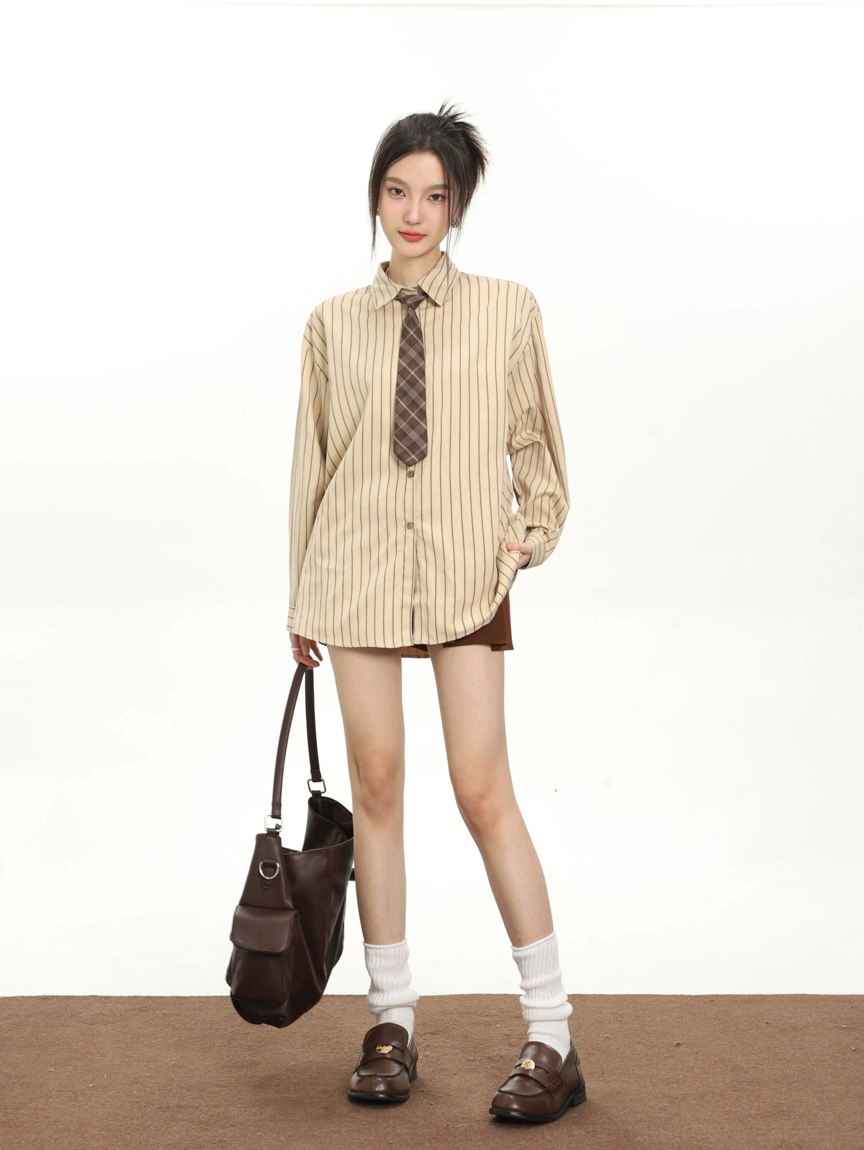 Khaki striped retro tie oversized long sleeve shirt for women paired with brown shorts and leather loafers