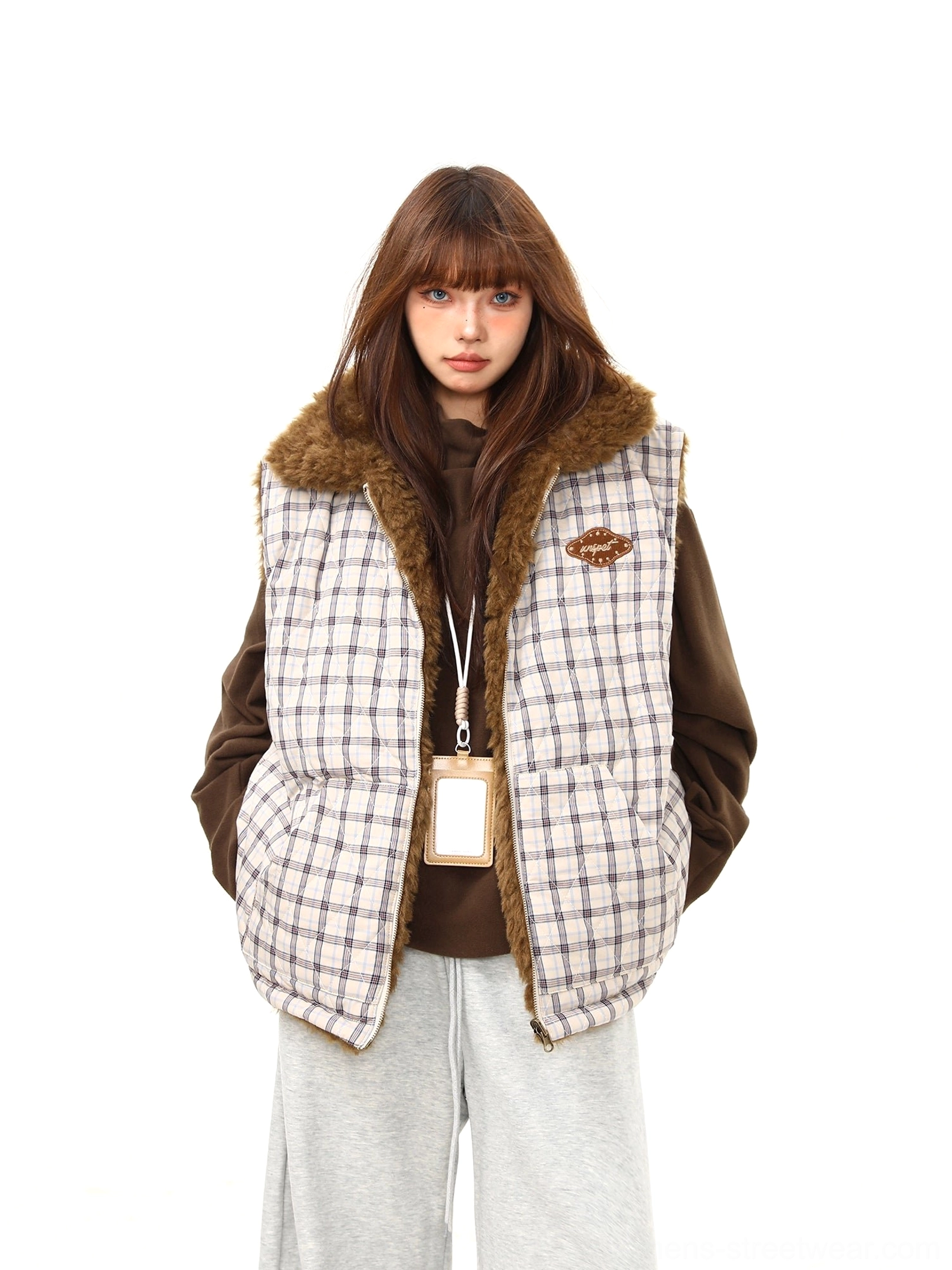 Front view of women's quilted plaid reversible sherpa vest with brown fleece collar, chest patch and zip closure