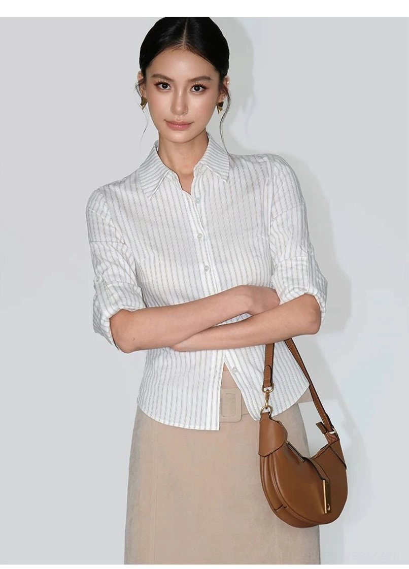 Women's rolled-sleeve pinstripe shirt styled with a beige midi skirt and brown half-moon shoulder bag