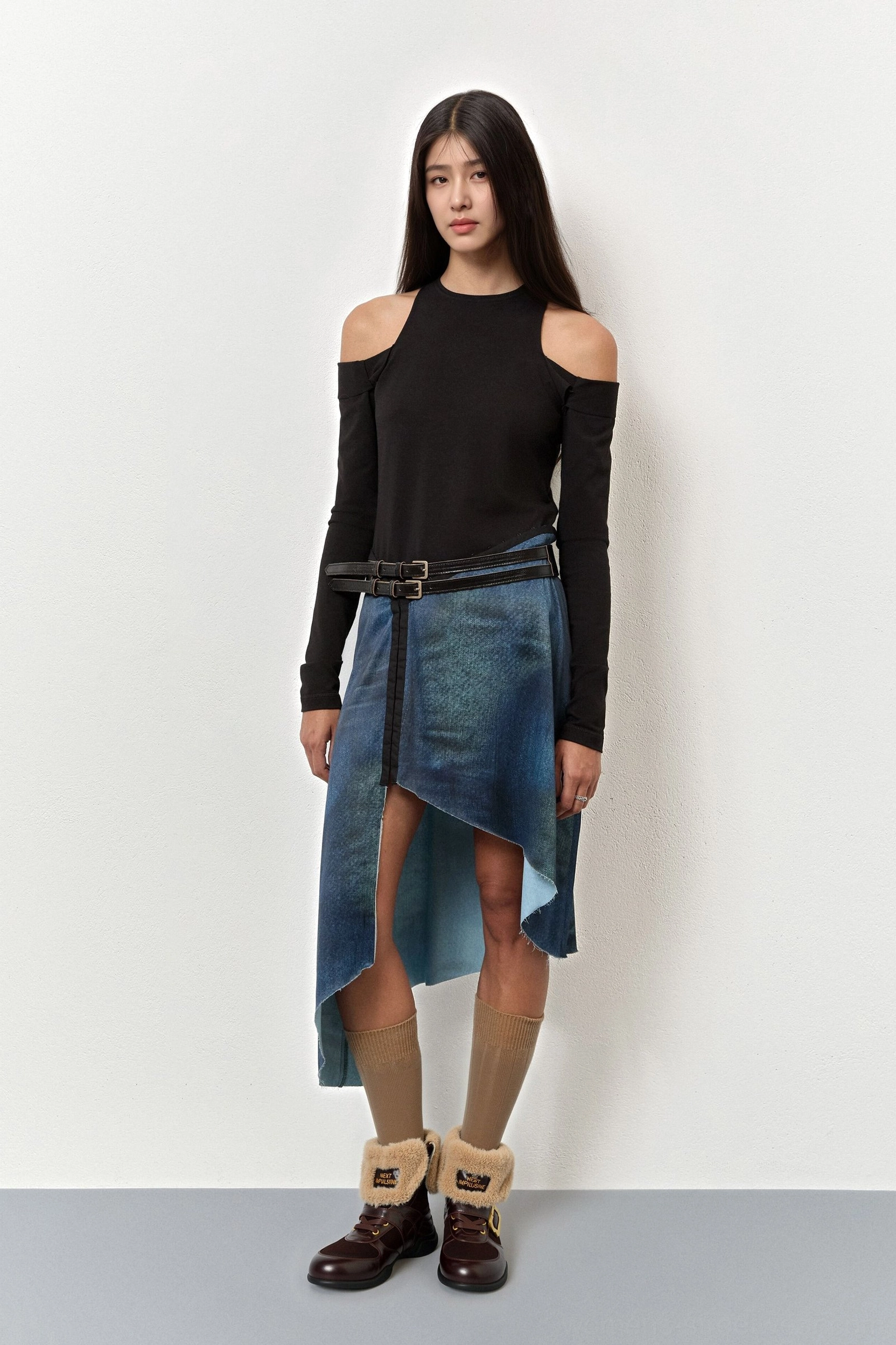 Women's shearling-cuff leather ankle boots styled with a black top and asymmetrical denim skirt