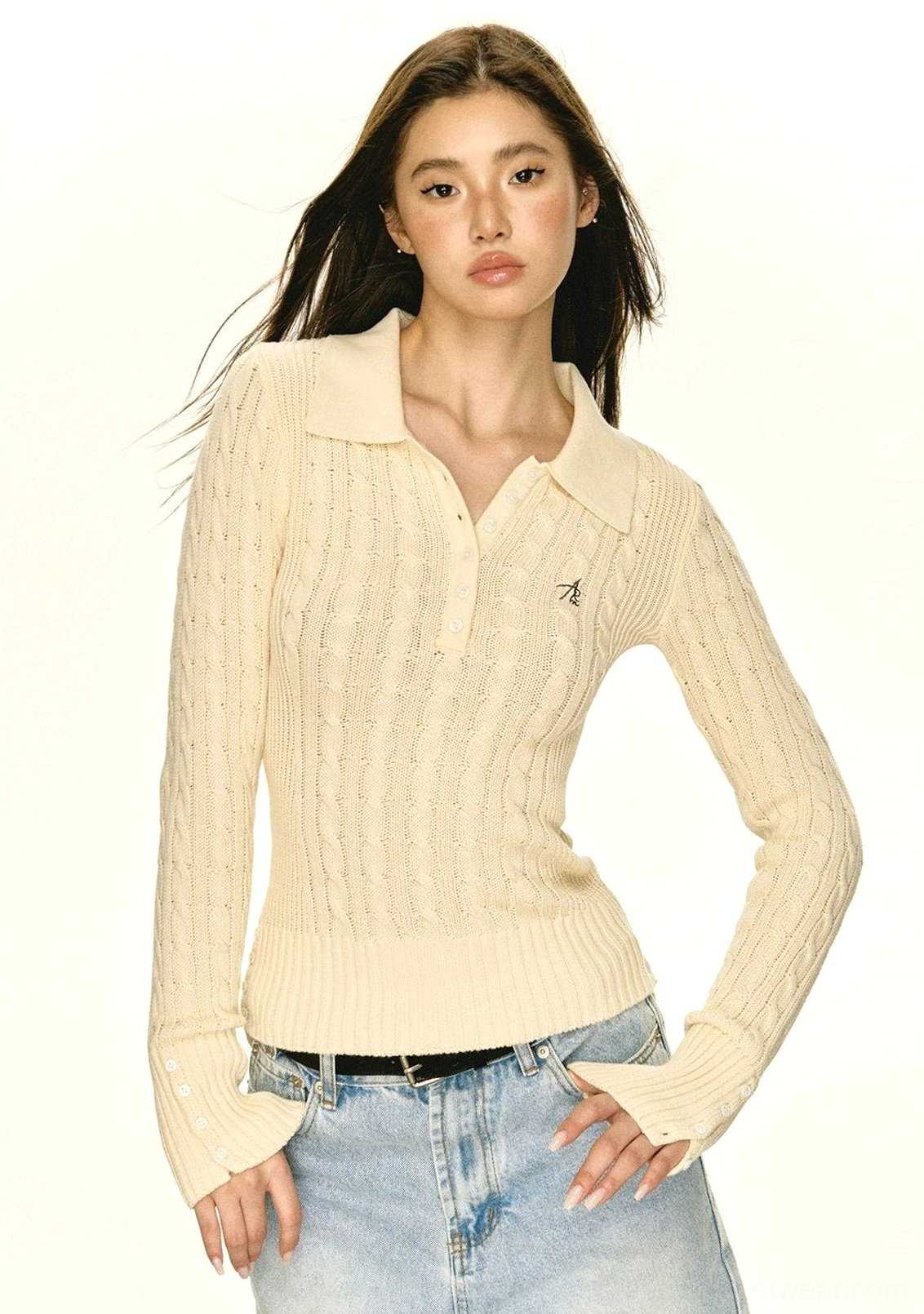 Front view of beige women's cable knit polo sweater with half-button placket and embroidered chest accent