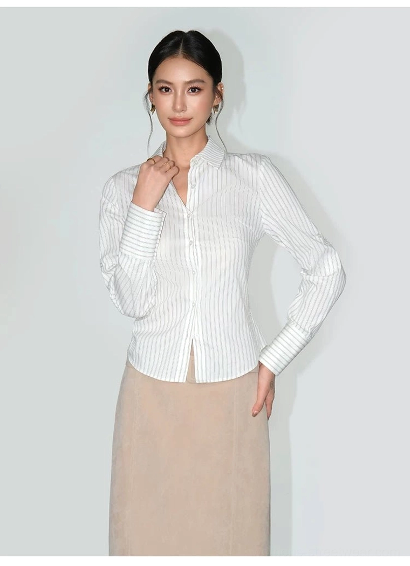 Front view of a women's slim-fit long-sleeve pinstripe shirt with button cuffs styled with a beige midi skirt