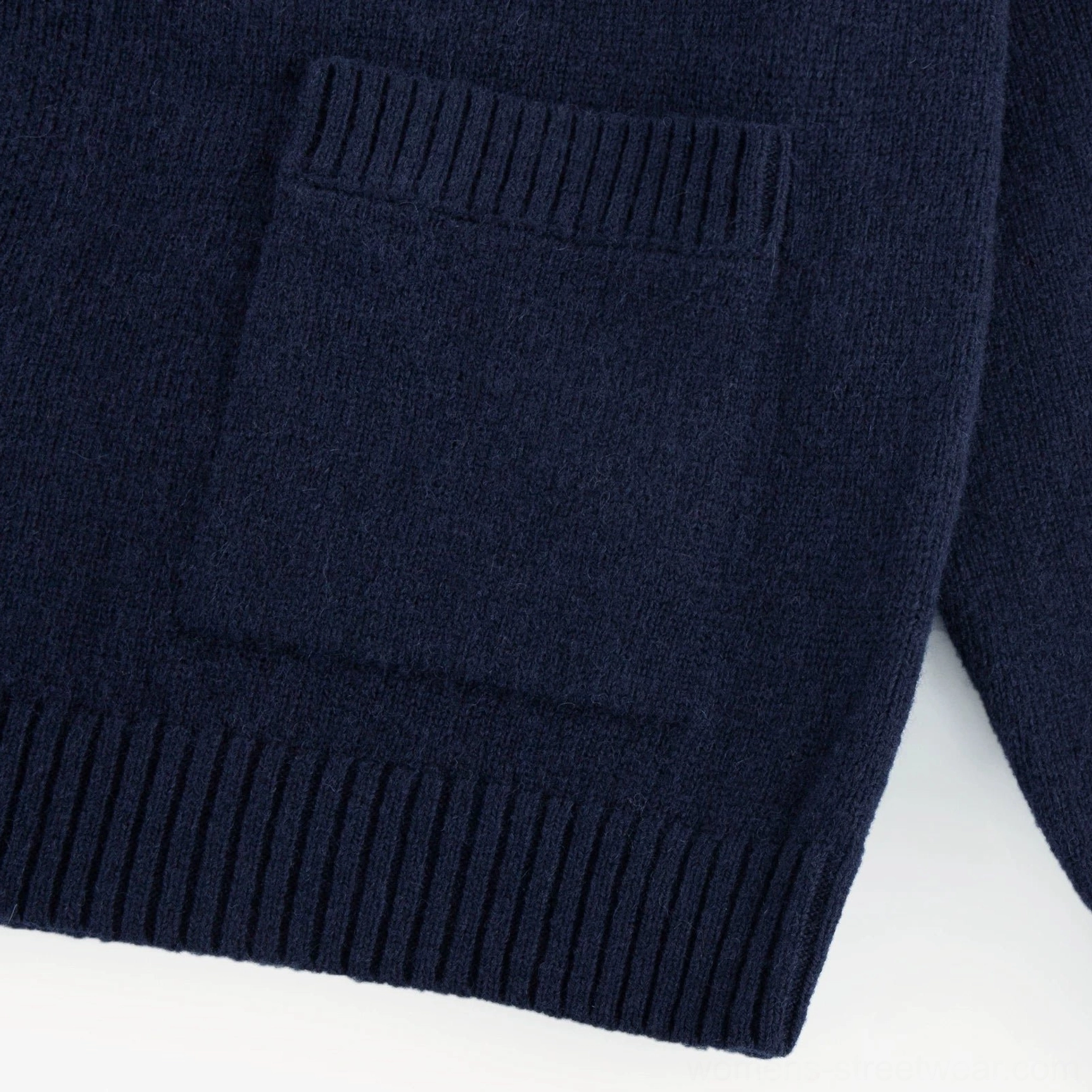 Close-up of front patch pocket and ribbed hem on dark blue women's RWS wool stand collar cardigan