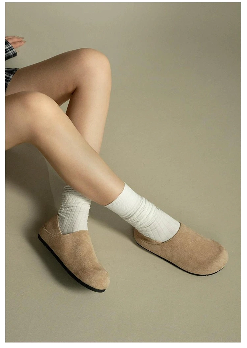Woman wearing light beige suede clogs with white ribbed socks in a relaxed minimalist everyday streetwear outfit