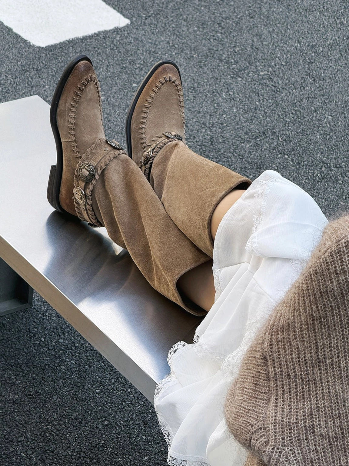 Women's suede western knee-high riding boots with buckle hardware, pointed toes, moc-toe stitching, and low stacked heels