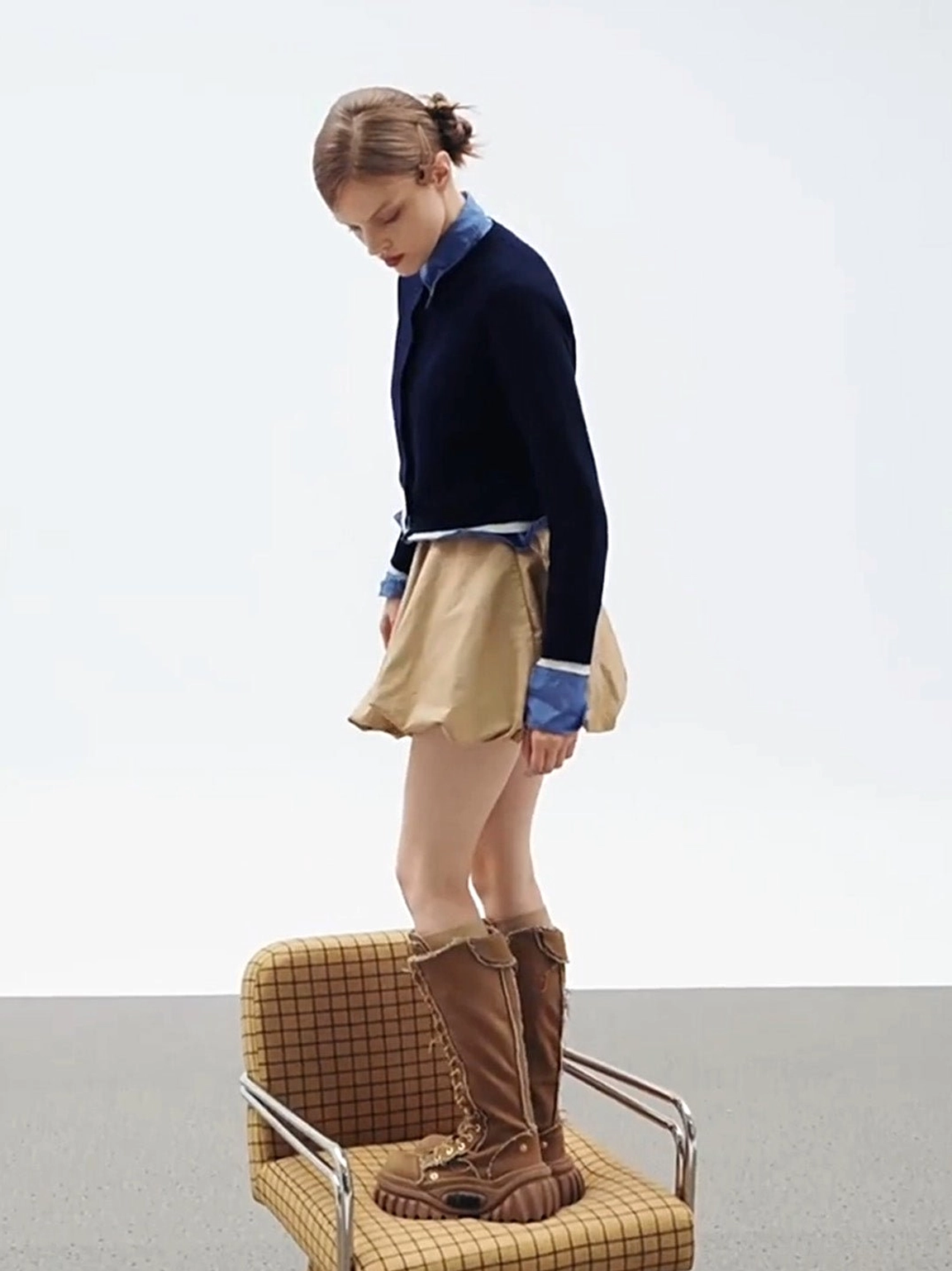 Brown knee-high lace-up platform riding boots styled with a Y2K preppy mini skirt outfit in side view