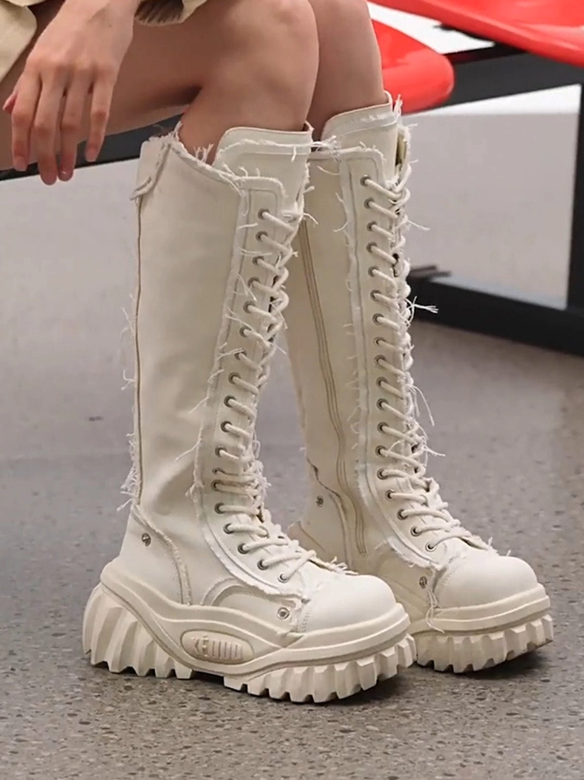 White women’s knee-high platform riding boots close-up showing frayed lace trim and chunky platform soles