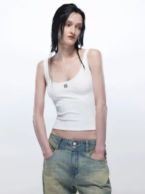 White women’s U-neck fitted tank top with metal logo badge styled with low-rise wide-leg blue jeans front view