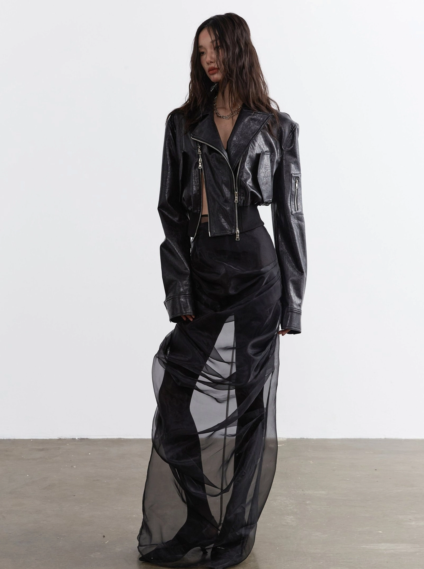 Women's ultra-cropped black faux leather biker jacket product image with asymmetrical zipper, silver-tone hardware, notched lapels, relaxed streetwear fit, and ribbed hem