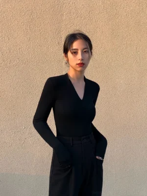 Black women's V-neck ribbed knit top with slim long sleeves styled in a fitted streetwear silhouette