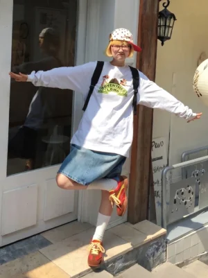 Woman wearing vintage colorblock low-profile trainers with a printed white T-shirt, denim skirt and polka dot bucket hat in a casual streetwear outfit
