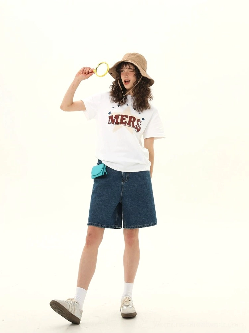 Women's white vintage MERS star varsity graphic tee styled with denim shorts and a crossbody bag full body view