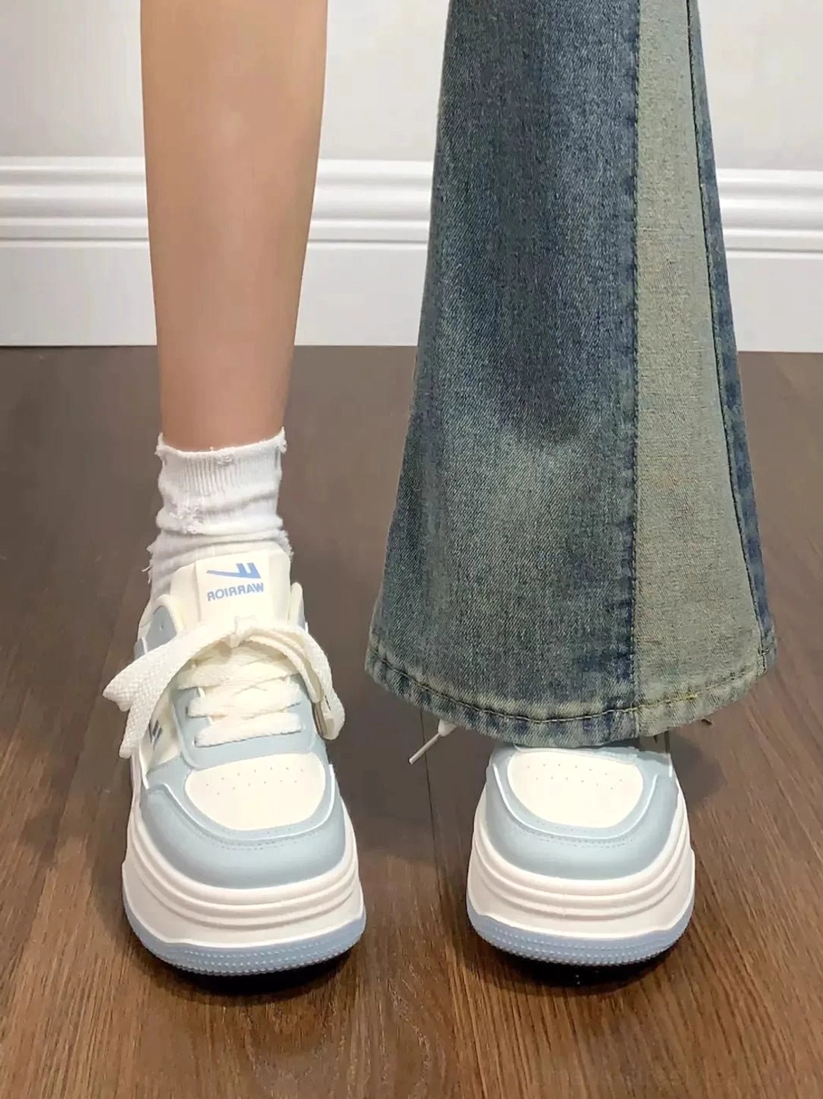 Women's white and light blue contrast sole platform sneakers worn with patchwork flare jeans and white crew socks