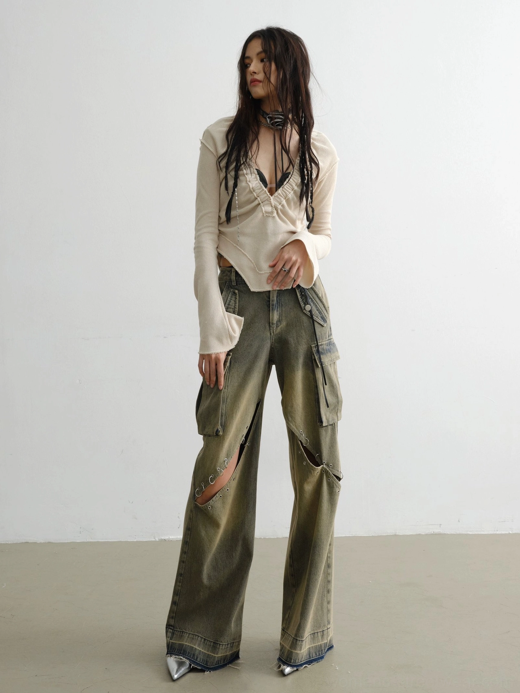 Side view of womens white deep V ribbed knit top with split flared sleeves and asymmetric hem styled for modern streetwear