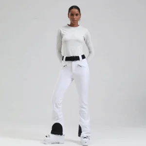 White women's flared ski pants with quilted side panels, black heel guards, zip pockets, and adjustable belt styled with ski boots