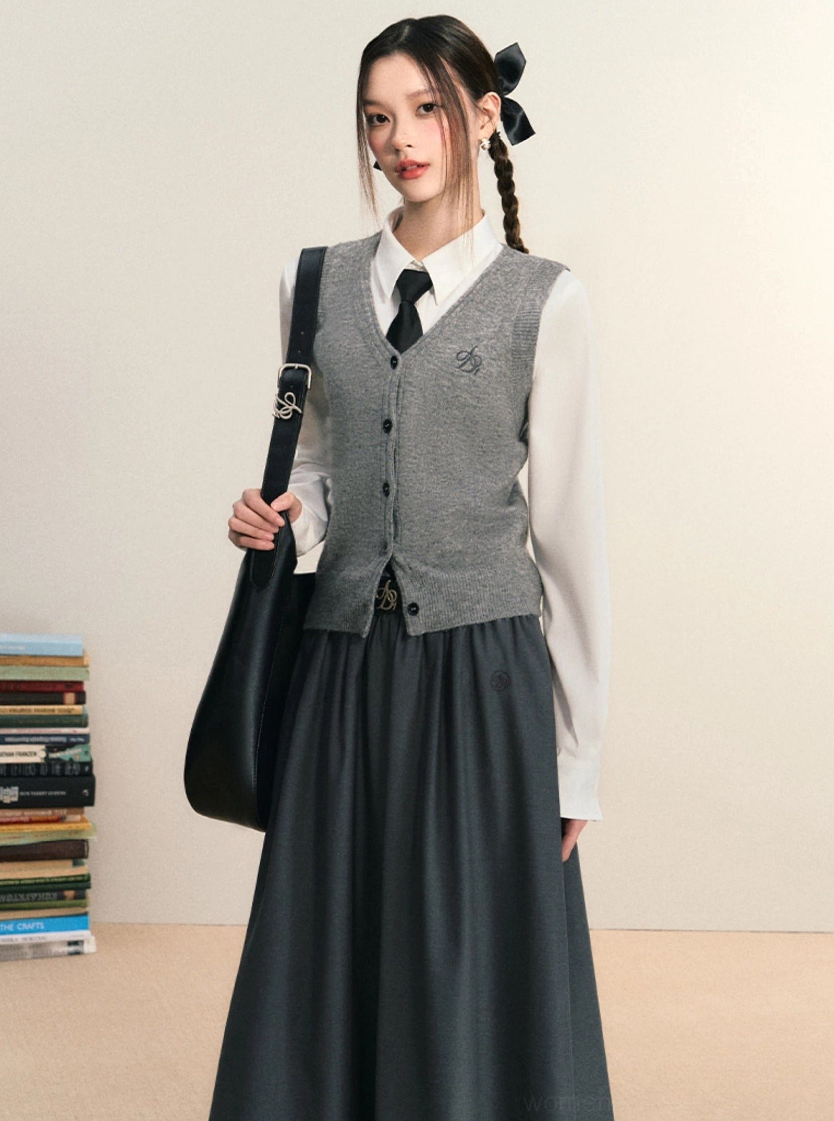 White women's button down shirt layered under a grey knit vest with long dark skirt in Seoul preppy style