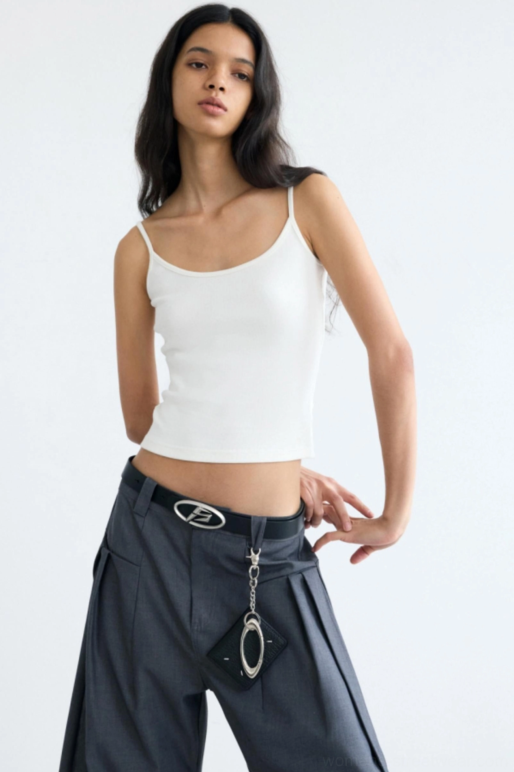 Women's white minimalist cropped camisole streetwear tank top with spaghetti straps styled with gray wide-leg trousers