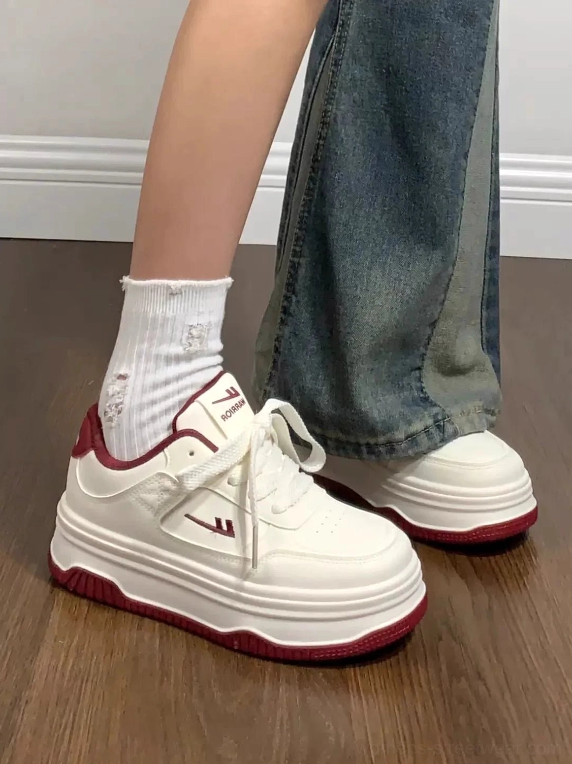 Women's white platform casual sneakers with red outsole and heel accent worn with patchwork flare jeans
