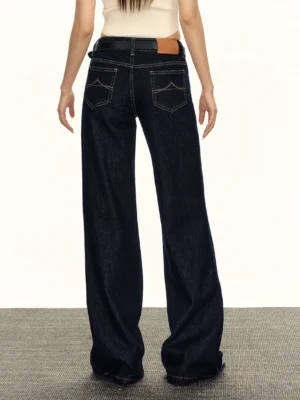 Rear view of women's wide-leg denim jeans showing decorative back pocket stitching, leather waist patch, dark indigo wash, and relaxed streetwear fit