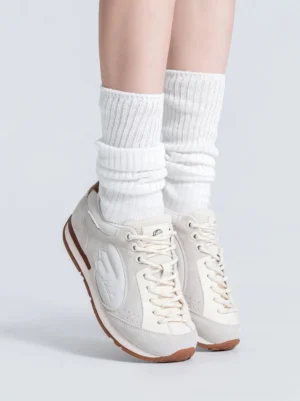 Women's gray white wing panel retro court sneakers worn with white crew socks front low angle streetwear view