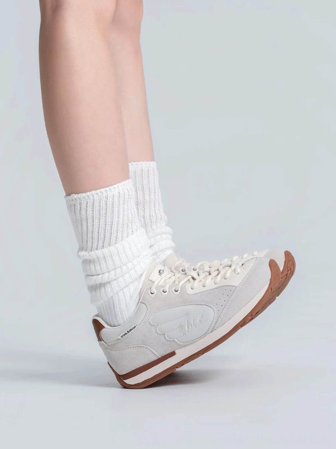 Women's wing panel retro court sneaker gray white low top profile worn with white crew socks and visible gum sole