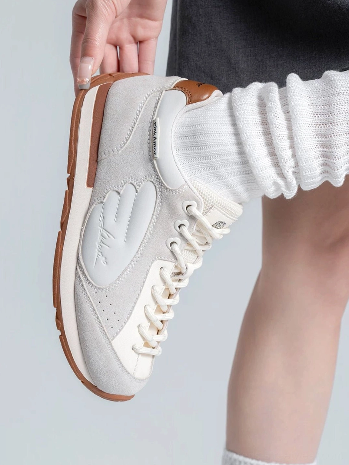 Close-up of women's gray white wing panel retro court sneaker showing textured upper raised side overlay and brown heel detail