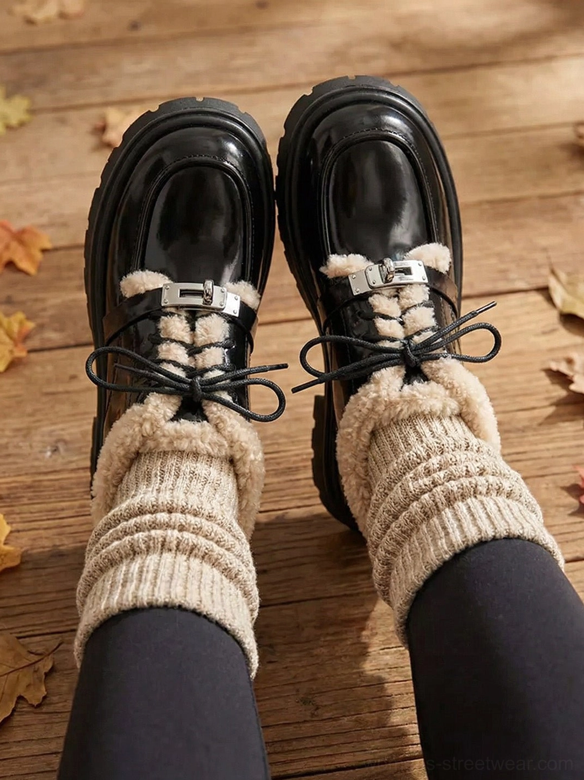 Worn black patent platform Oxford shoes with visible beige fleece collar, metal lace buckle, and black tights outdoors