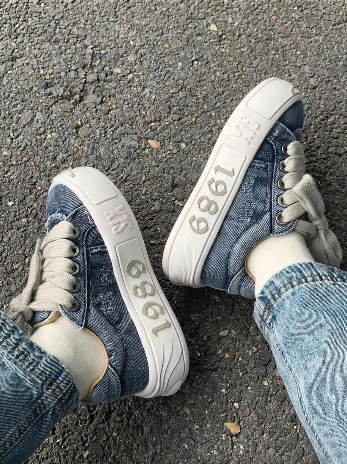 Overhead view of worn blue denim skate sneakers paired with jeans and thick flat laces for a Y2K streetwear look