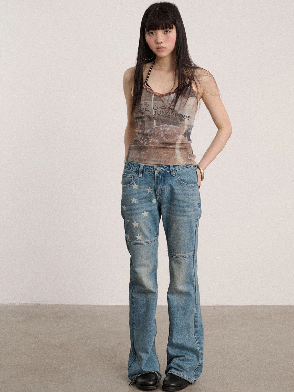 Front view of worn light blue star patterned low-rise flared jeans with a clean long-leg silhouette and graphic panels
