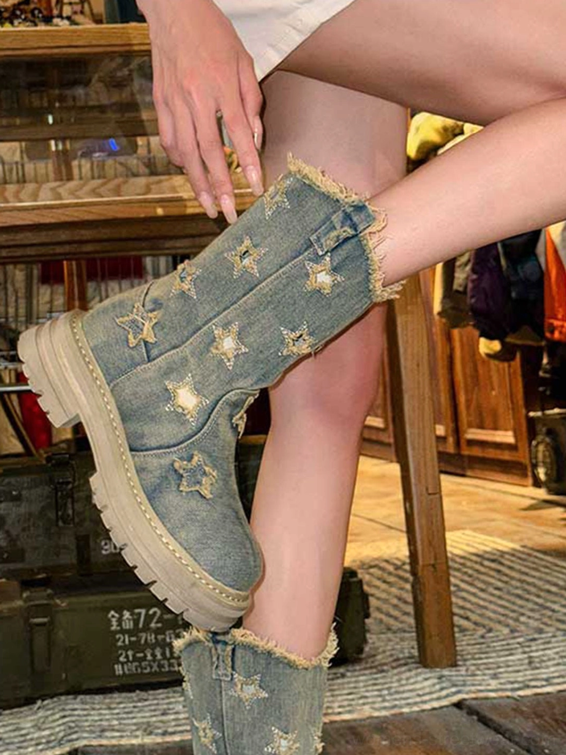 Side view of worn washed blue distressed denim platform boots with frayed collar, star details, and thick lug rubber outsole