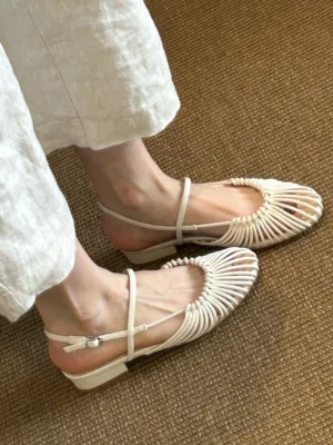 Off-white woven cage Mary Jane sandals worn with cropped white linen pants, adjustable ankle strap and low block heel