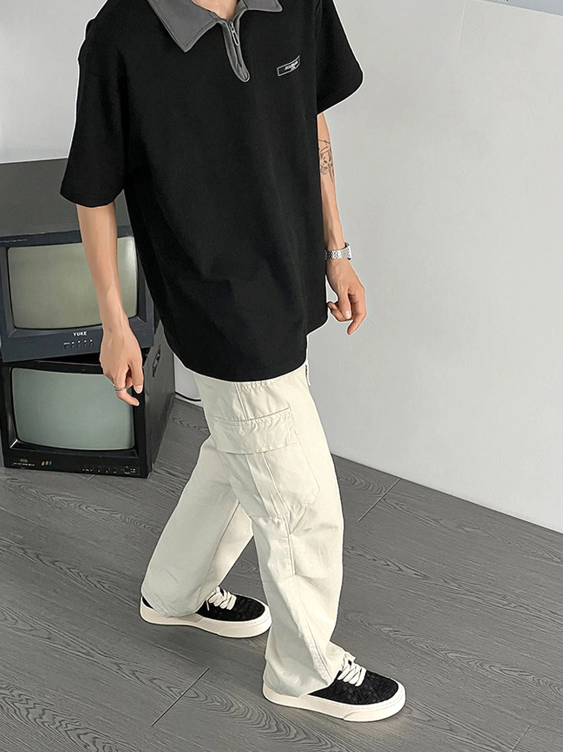Black woven platform sneakers styled with gray cargo pants and black polo shirt for casual streetwear