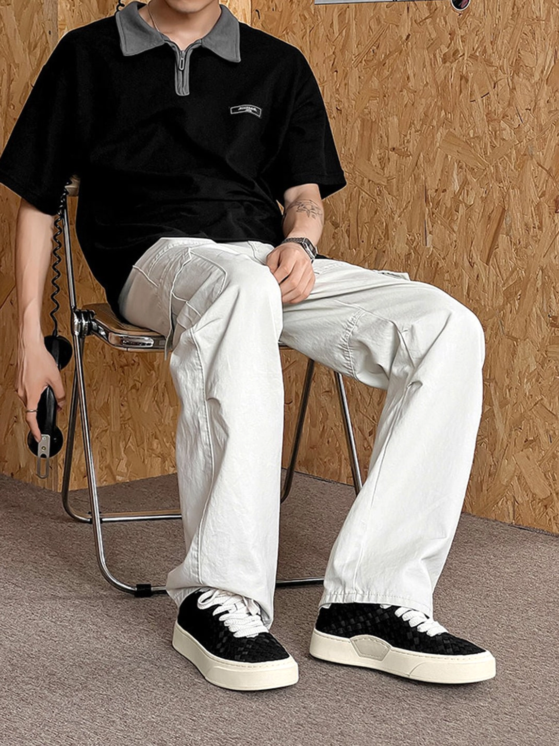 Black woven platform sneakers side view worn with relaxed gray wide-leg trousers indoors