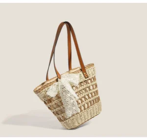 Three-quarter view of a woven straw basket tote with hollow grid texture, white lace bow, and brown faux-leather shoulder straps