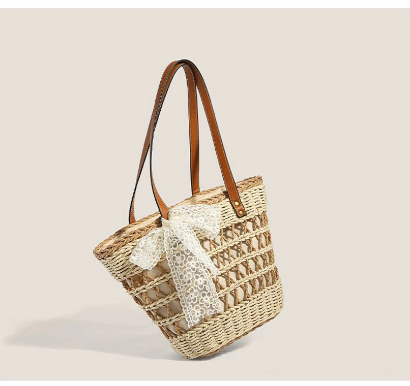 Three-quarter view of a woven straw basket tote with hollow grid texture, white lace bow, and brown faux-leather shoulder straps