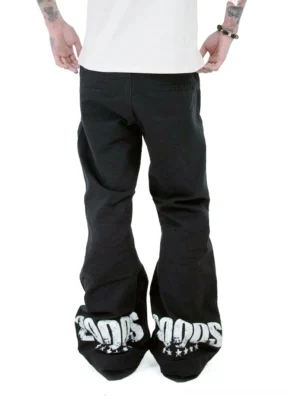 Rear close-up of black Y2K flare jeans showing bold white 2000S lettering and star graphics printed across the wide flared hems