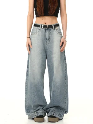 Front view of light blue washed Y2K baggy wide-leg jeans with high waist, oversized silhouette, long pooling hem, and black belt styled with a cropped black tank top