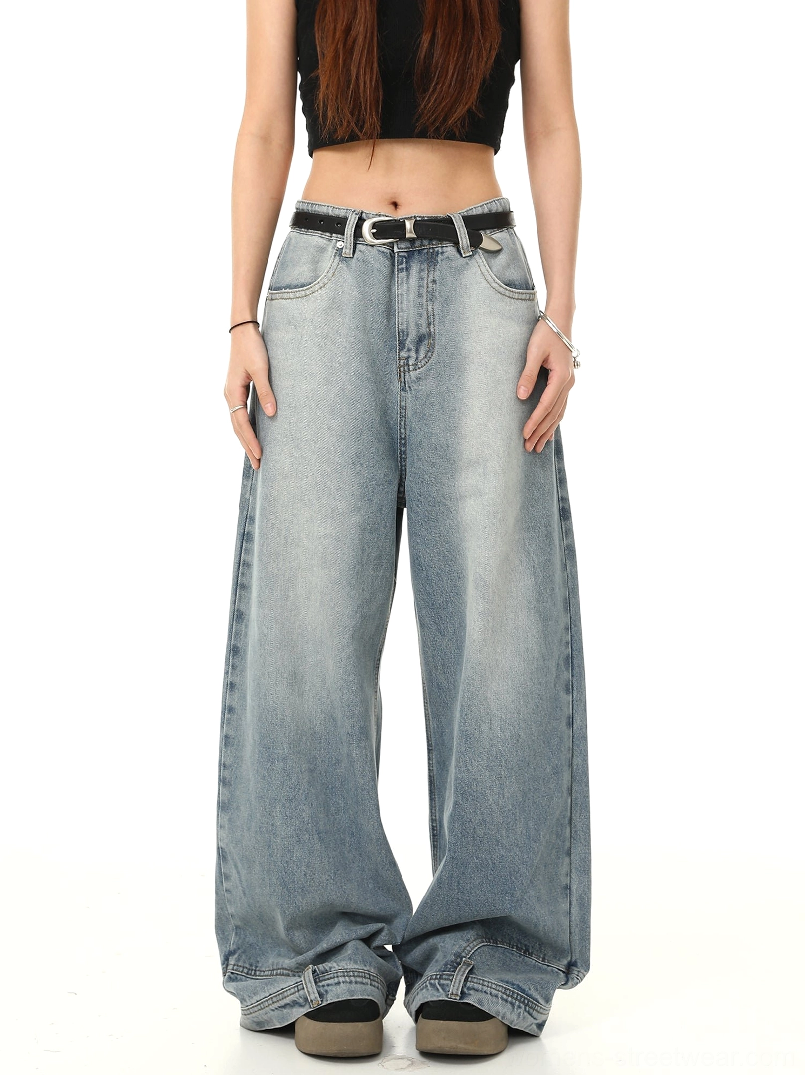 Front view of light blue washed Y2K baggy wide-leg jeans with high waist, oversized silhouette, long pooling hem, and black belt styled with a cropped black tank top