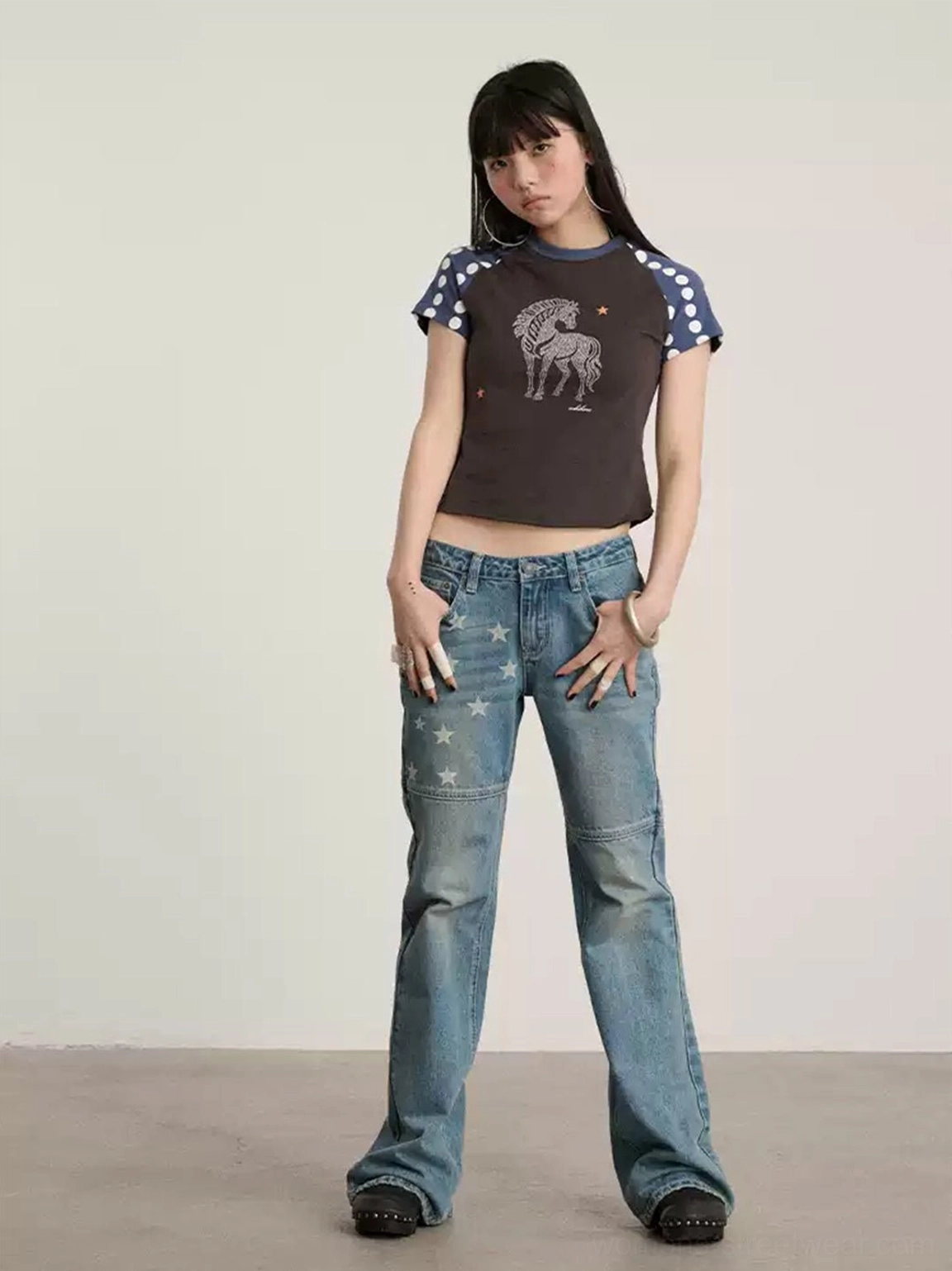 Y2K inspired blue low-waist star print flare jeans with faded denim, paneled construction, and graphic streetwear styling