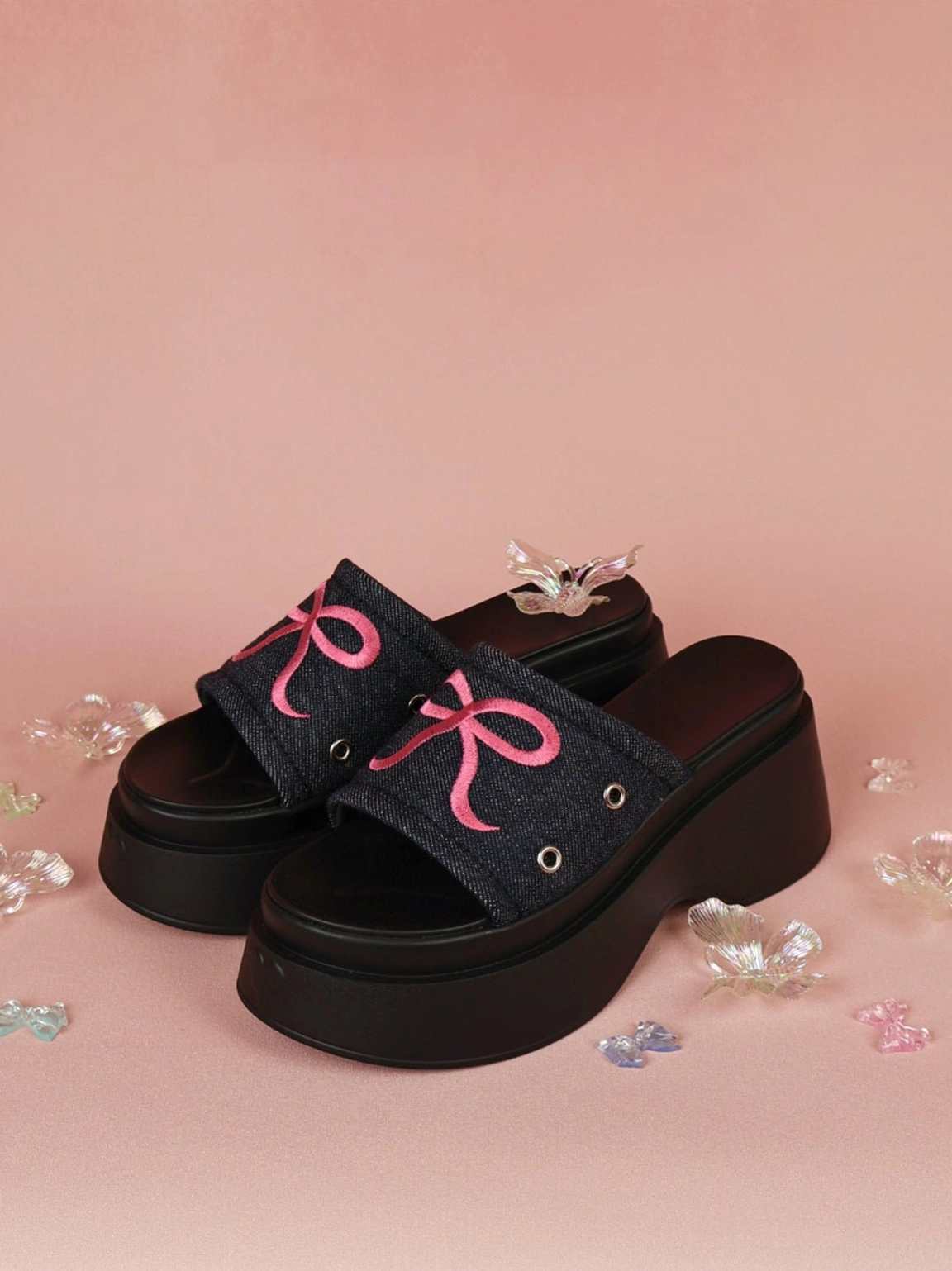 Y2K-inspired bow platform slide sandals with a bright pink sole and contrasting black strap