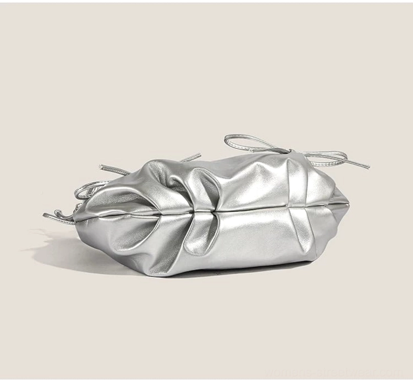 Overhead side view of silver ruched bow hobo shoulder purse with gathered base and zip top