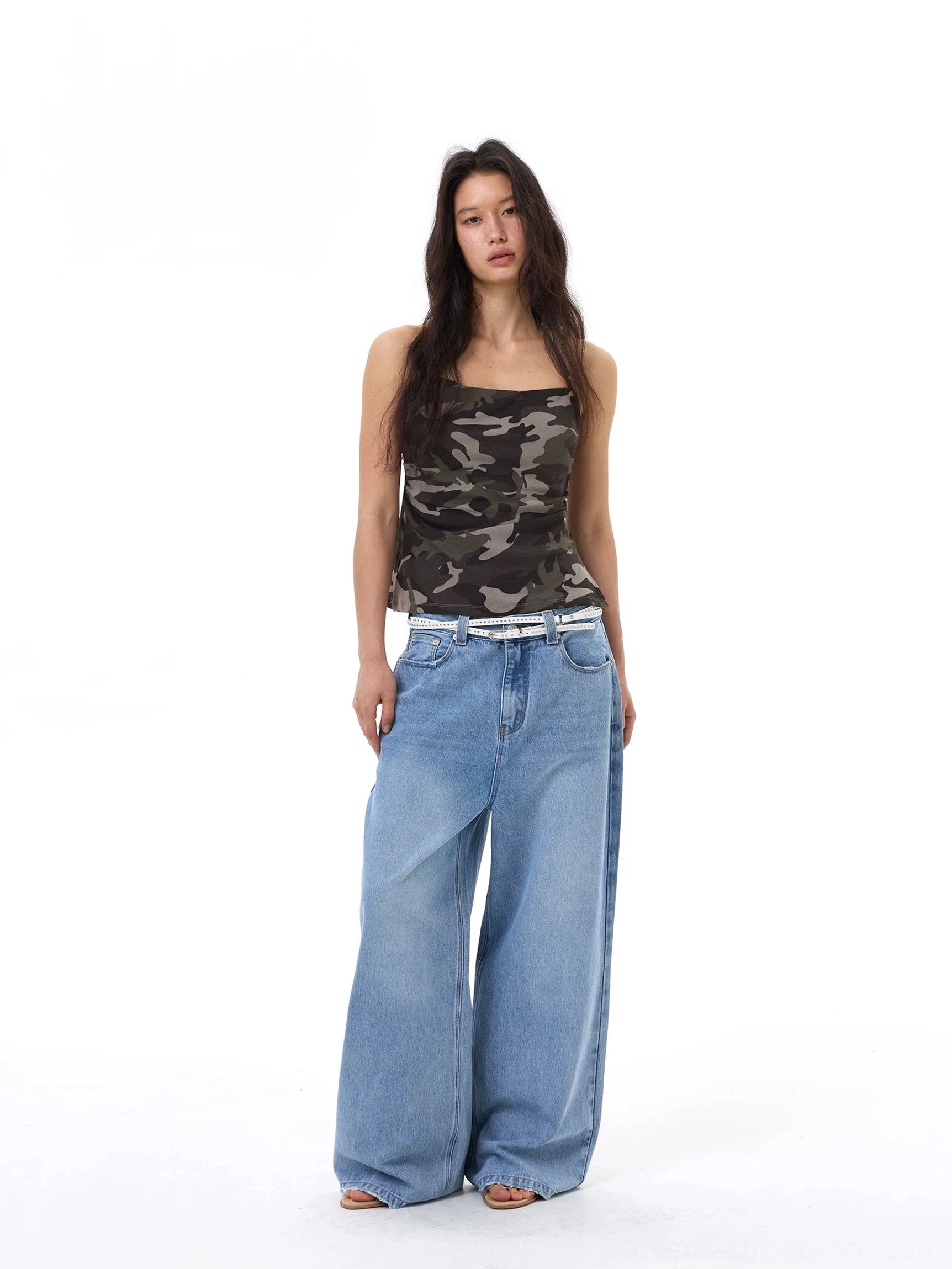 Full front view of a camouflage camisole top styled with light blue wide-leg jeans and a fashion belt