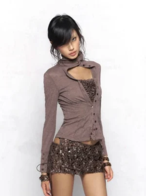 Front view of a fitted khaki and dark gray Y2K cut-out funnel neck button cardigan with built-in ruched camisole panel, slim waist, long sleeves, and heathered knit texture styled with a sequin mini skirt