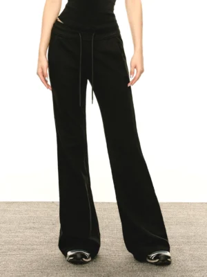 Front full-body view of a model wearing black Y2K flared slim-fit sweatpants with an adjustable drawstring waist, wide-leg silhouette, cropped black top, and sneakers