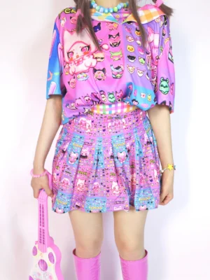 Front close-up of a kawaii cat print pleated mini skirt with pink-purple cartoon graphics, rainbow checkered waistband, pink knee-high boots, and guitar-shaped handbag in a Y2K Harajuku streetwear outfit