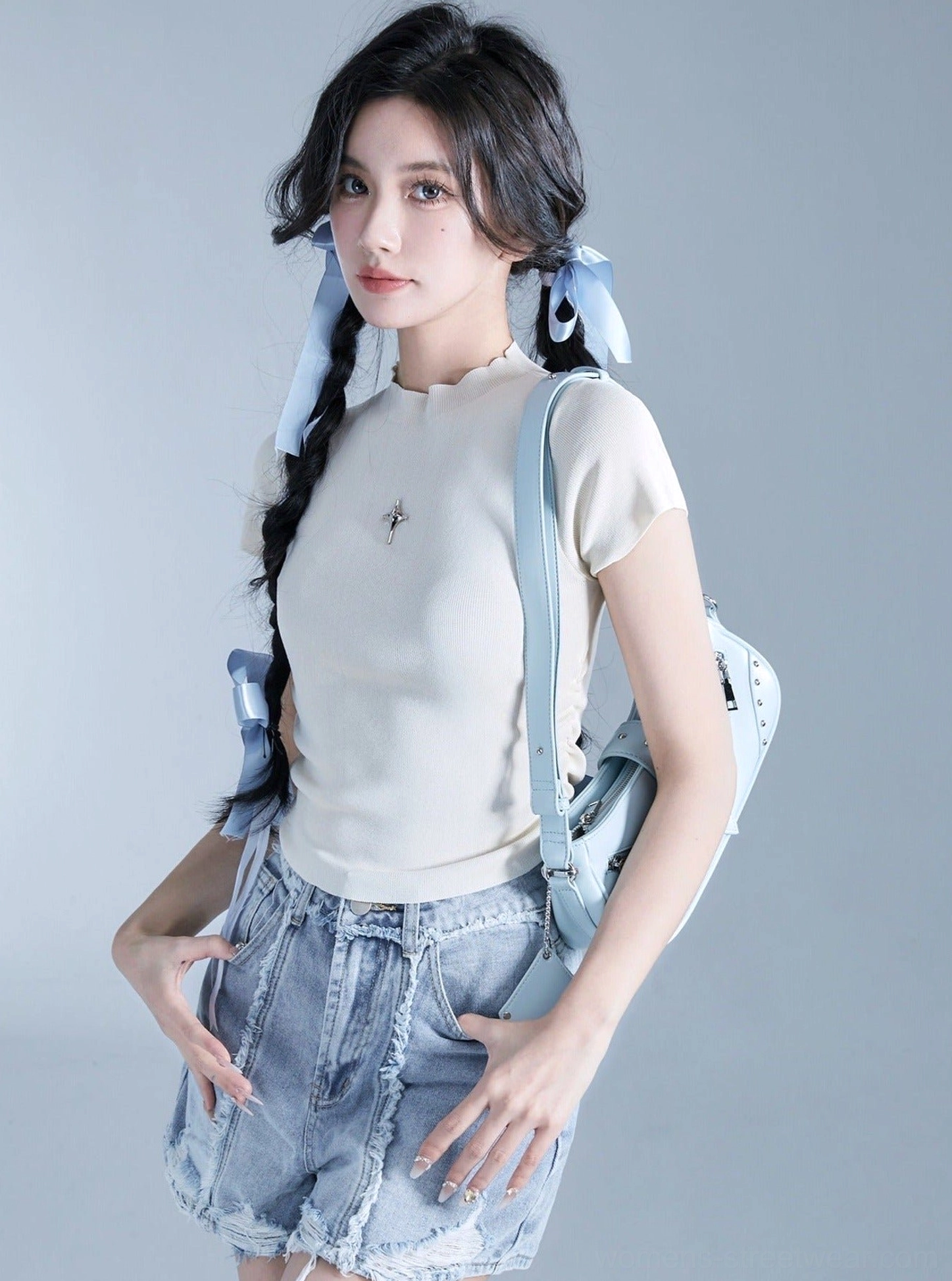 Light blue multi-zip Y2K shoulder bag with matching strap, silver decorative zippers, and buckle detail worn with denim shorts