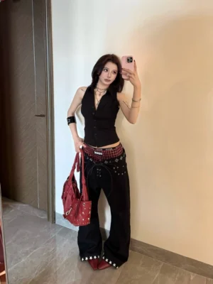 Front mirror selfie showing Y2K punk wide leg black jeans with red plaid double waistband, star rivet trim, and oversized streetwear silhouette
