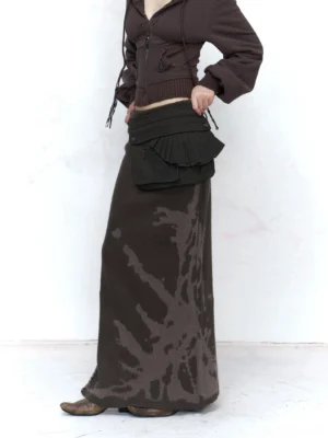 Front three-quarter view of a dark gray brown Y2K tie-dye knitted maxi skirt with high side slit, utility waist pouch, cropped hoodie, and leather ankle boots